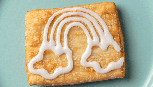 An animated GIF of a person using frosting to draw a rainbow on a toaster strudel.